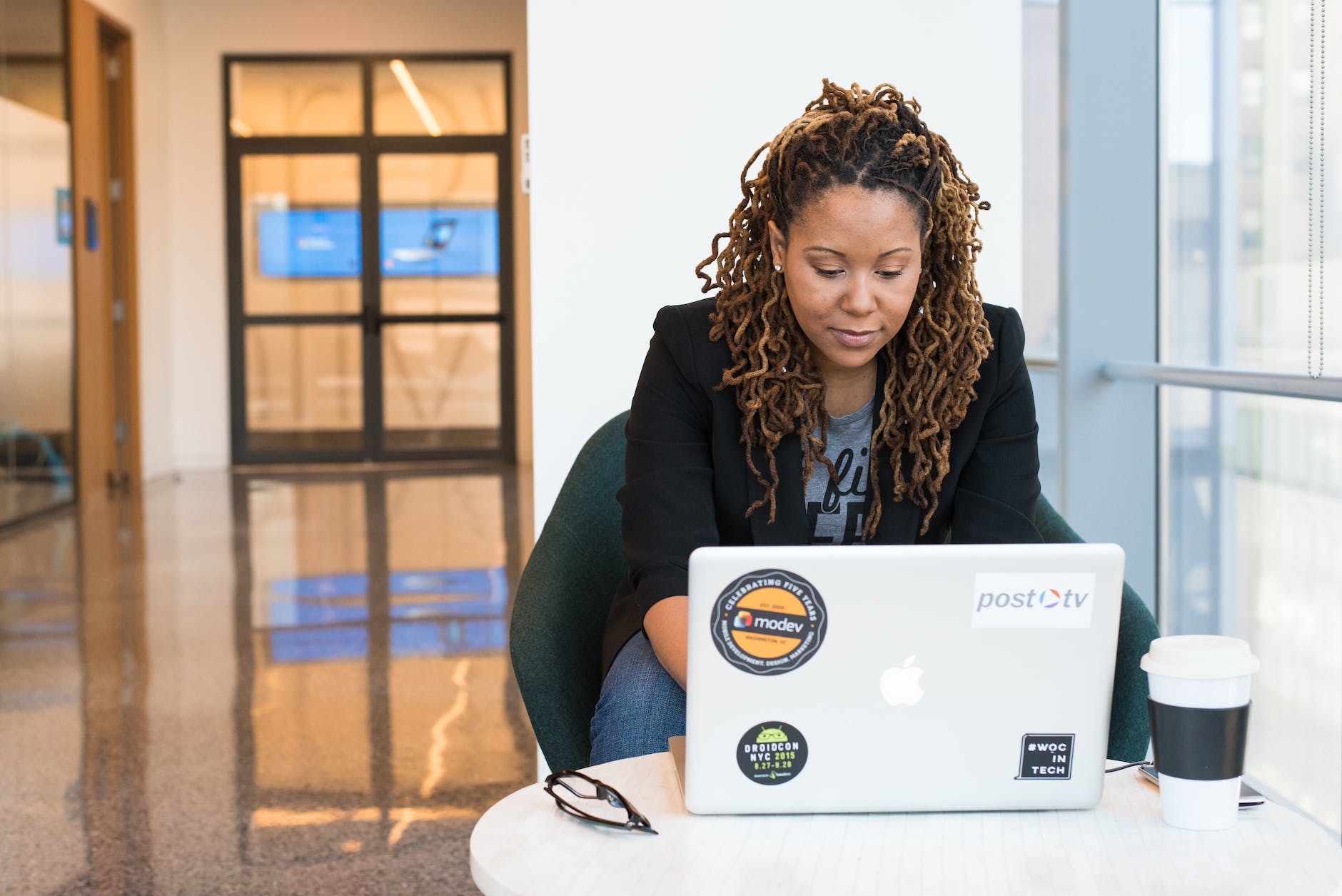 woman in black blazer sitting on black chair using laptop