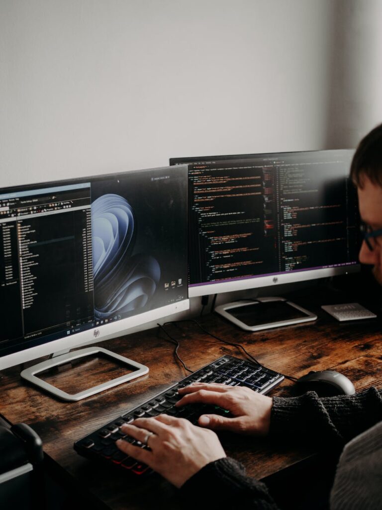 man sitting at desk working on computers