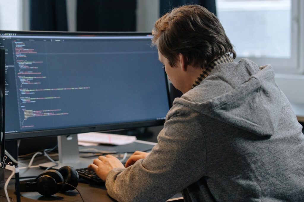 man sitting in gray hoodie jacket typing on a computer keyboard