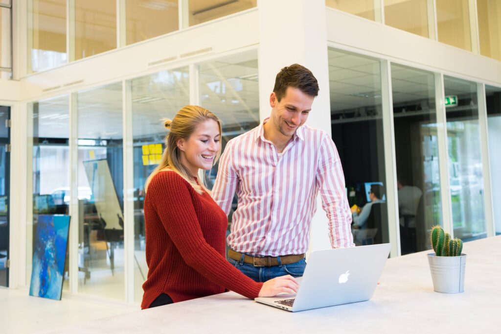 man and woman beside table with macbook