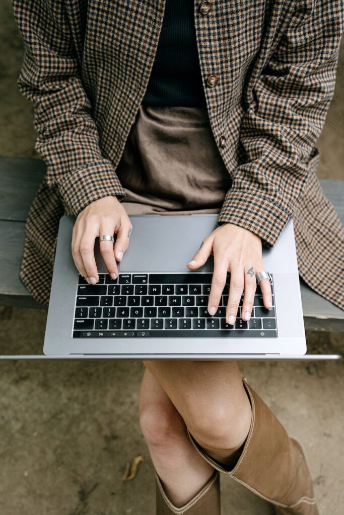 woman in brown checkered coat using a laptop