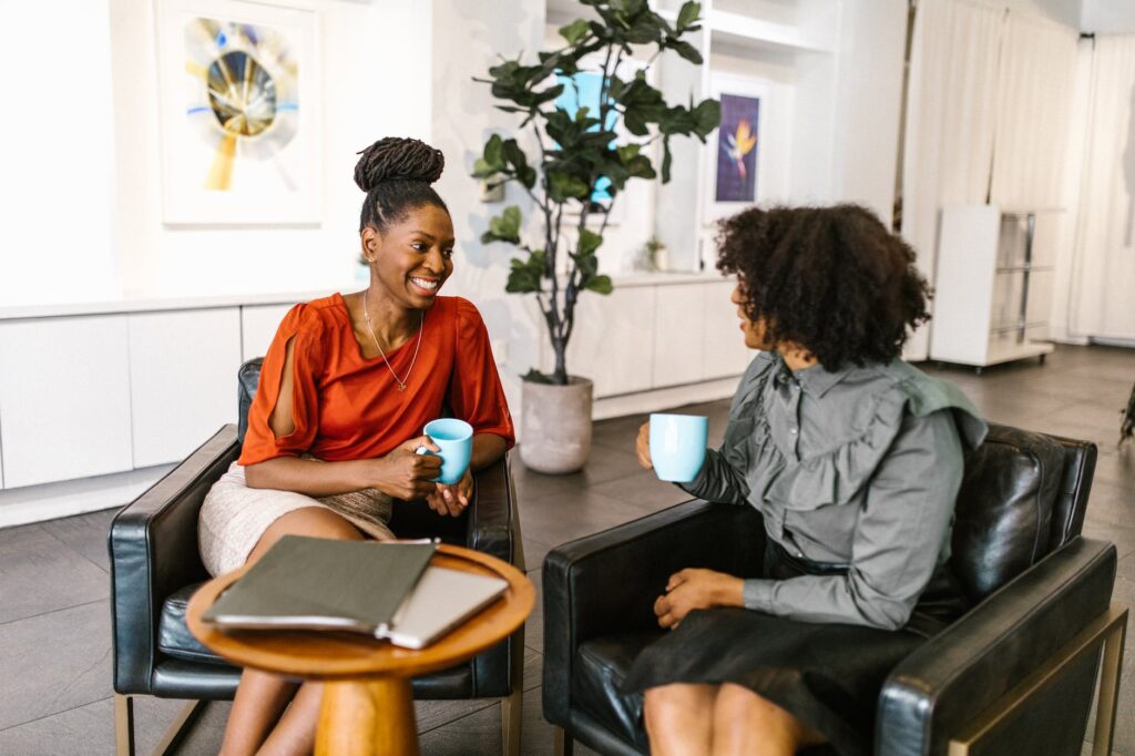 women sitting on the chair while having conversation