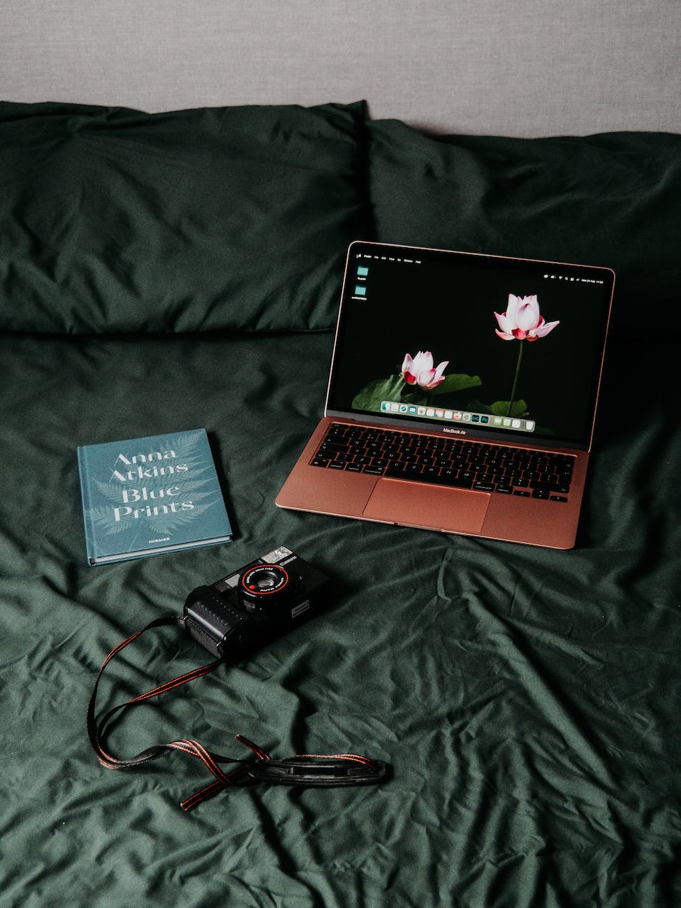 book and laptop and camera on bed