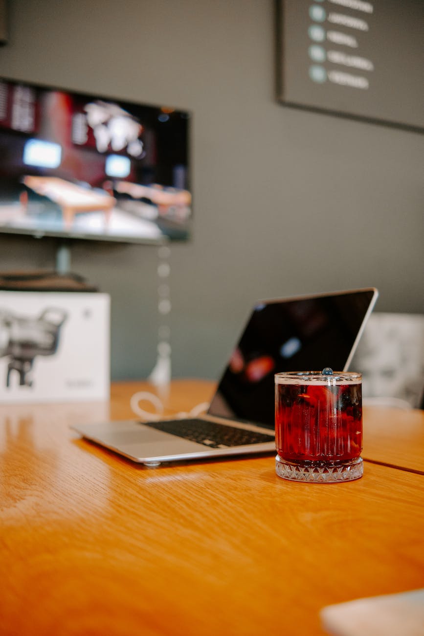 a laptop and a glass of juice on the table