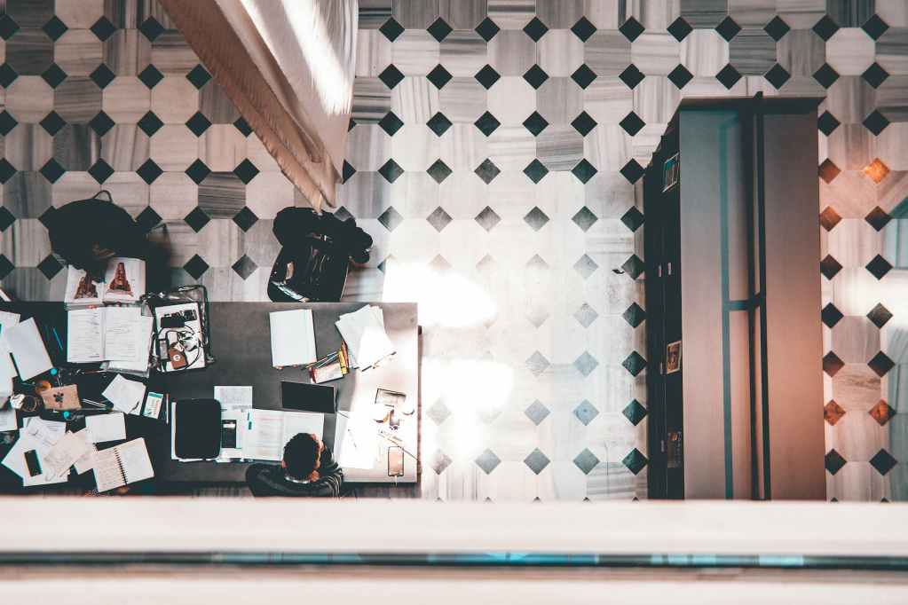 top view of people sitting on chairs beside table with books and papers
